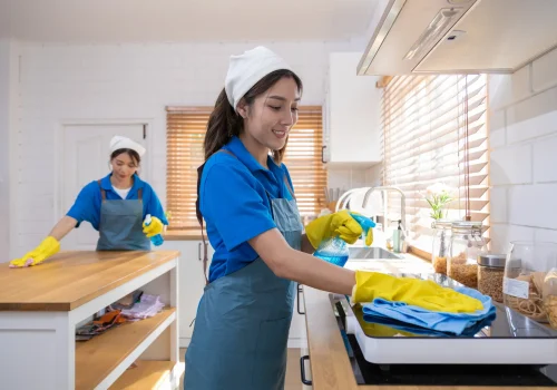 Two cleaning service crew cleaning the kitchen of the client's house.