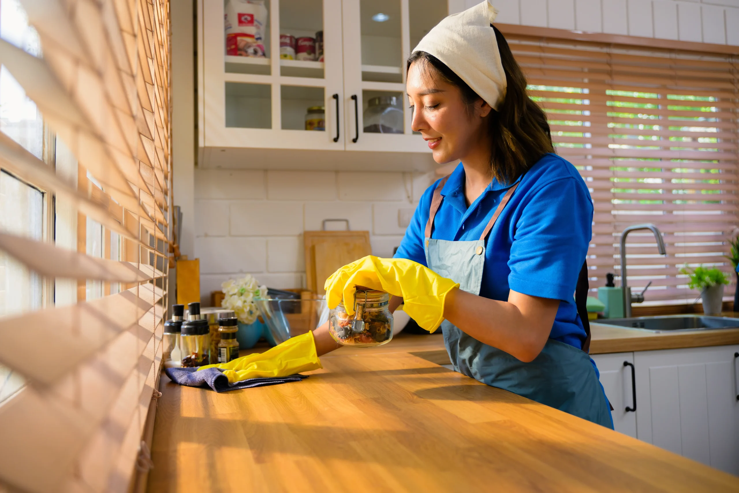 A woman cleaning the countertop of the kitchen.
