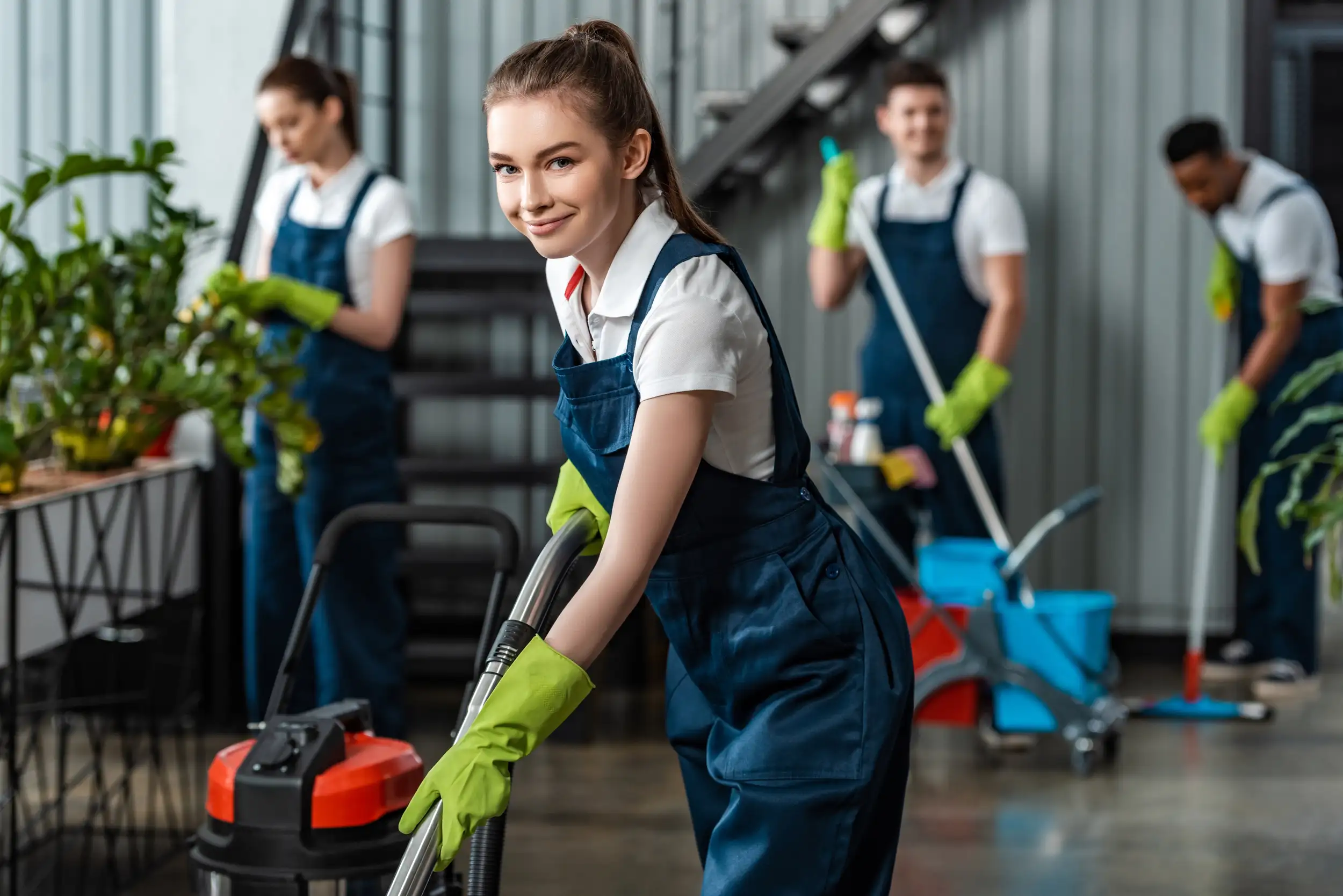 A woman that is smiling and cleaning with her co-workers.